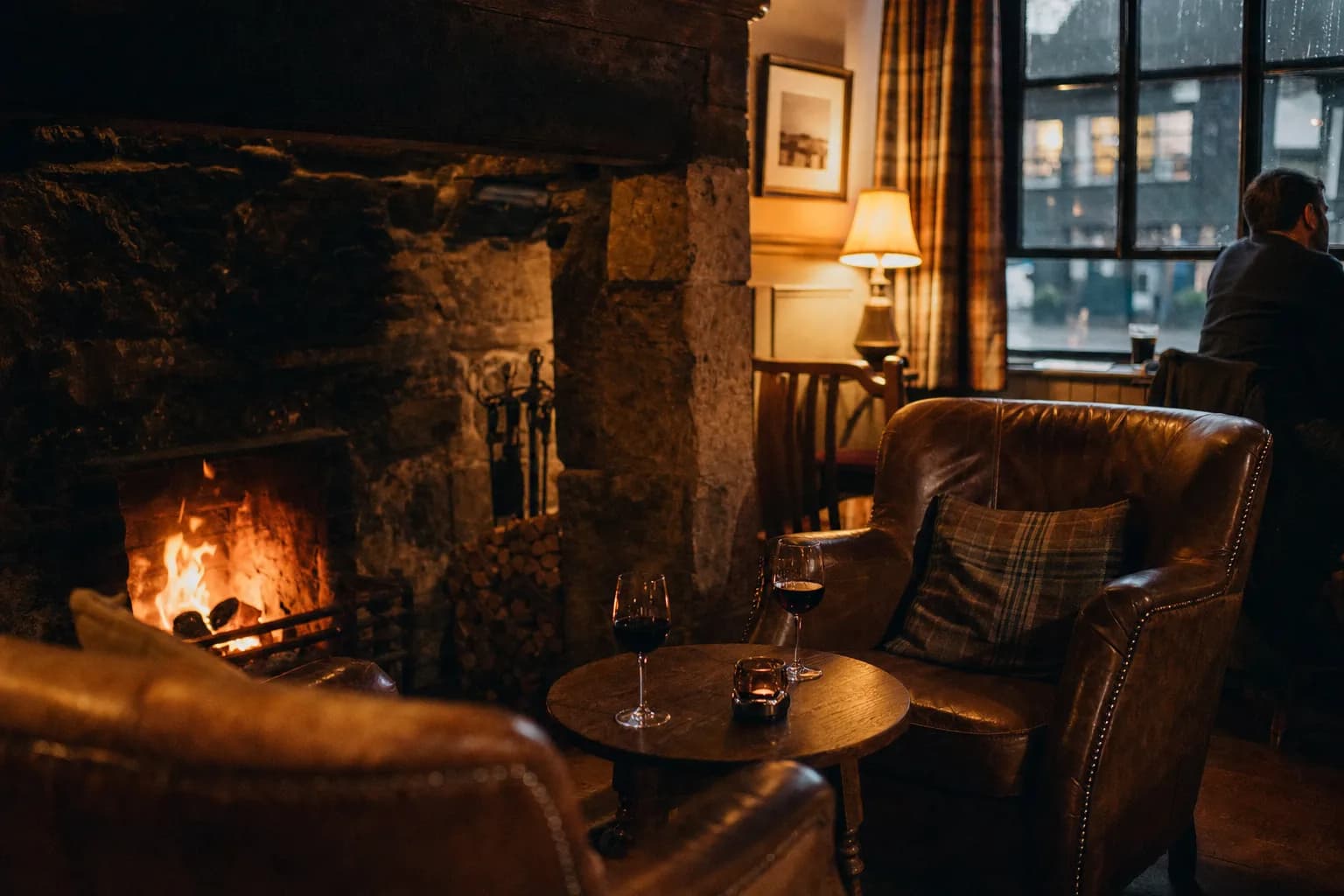 A fire-lit pub snug with leather armchairs and two glasses of red wine (AI example photo)