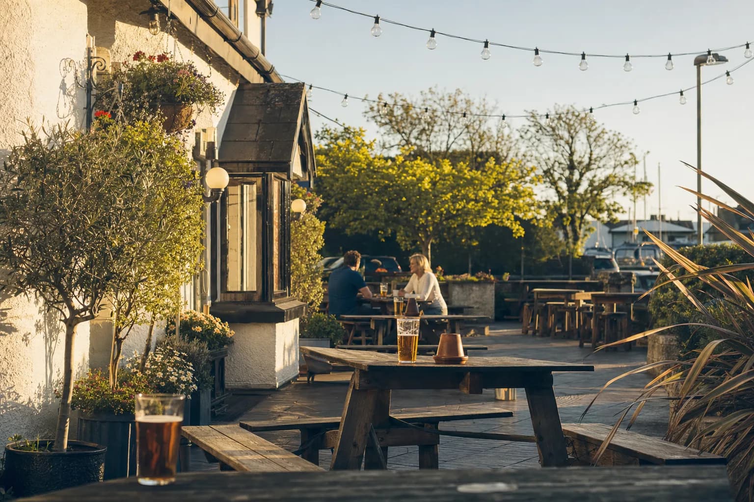 A pub terrace in late afternoon sun, with pints on the tables (AI example photo)